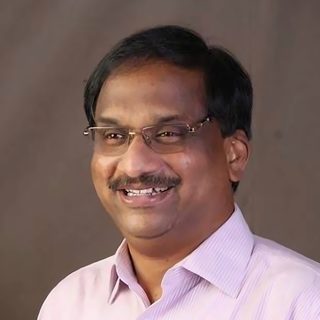 Prof. K. Nageshwar, laughing, in a striped shirt